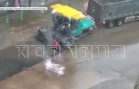 Стоя по колено в воде дорожные рабочие кладут асфальт на дорогу